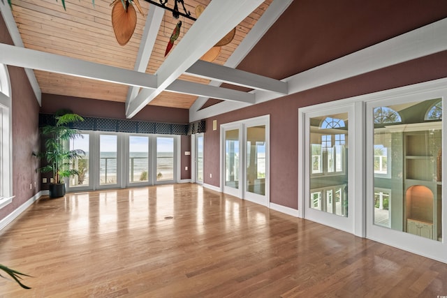 interior space with a water view, a wealth of natural light, hardwood / wood-style flooring, and vaulted ceiling with beams