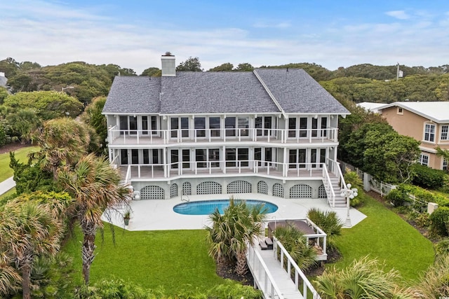 rear view of house with a fenced in pool, a yard, and a balcony