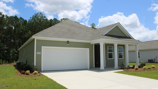 view of front of house featuring central air condition unit, a front yard, and a garage