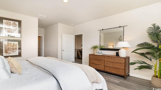 bedroom featuring dark hardwood / wood-style flooring and ensuite bathroom