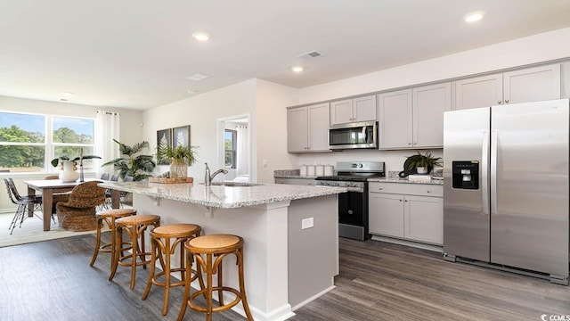 kitchen featuring gray cabinetry, sink, dark hardwood / wood-style flooring, a center island with sink, and appliances with stainless steel finishes