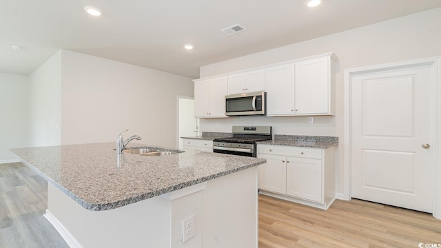 kitchen featuring white cabinetry, an island with sink, light hardwood / wood-style floors, and appliances with stainless steel finishes