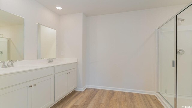 bathroom with hardwood / wood-style floors, vanity, and a shower with shower door