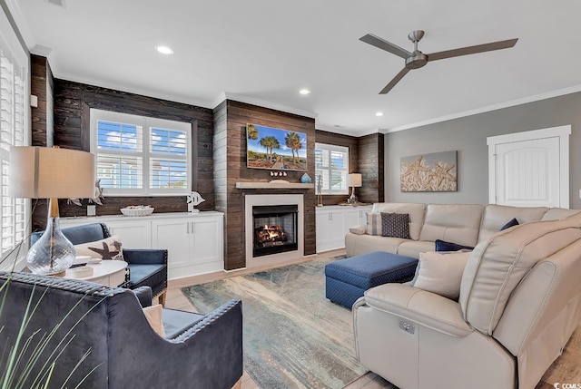 living room with wood walls, light hardwood / wood-style flooring, ceiling fan, and ornamental molding