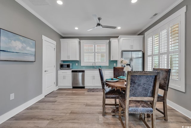 interior space featuring appliances with stainless steel finishes, light hardwood / wood-style flooring, white cabinets, and ceiling fan