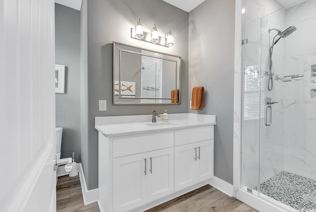 bathroom with hardwood / wood-style flooring, a shower with shower door, toilet, and vanity