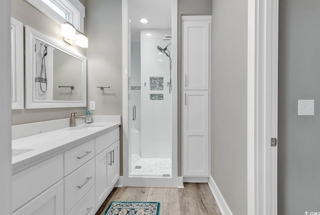 bathroom with a shower with door, dual bowl vanity, and hardwood / wood-style floors