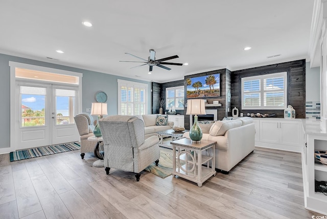 living room featuring ornamental molding, wood walls, ceiling fan, and light wood-type flooring