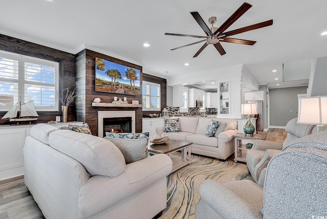 living room with light hardwood / wood-style floors, wood walls, and ceiling fan