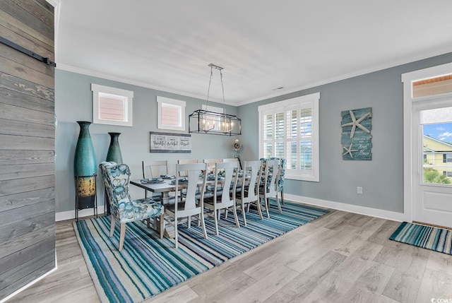 dining space featuring a chandelier, light hardwood / wood-style floors, crown molding, and a wealth of natural light