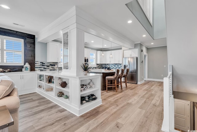 kitchen with backsplash, stainless steel fridge, light hardwood / wood-style flooring, and a wealth of natural light