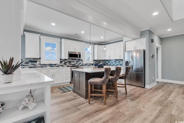 kitchen featuring white cabinetry, stainless steel appliances, hanging light fixtures, decorative backsplash, and light hardwood / wood-style floors