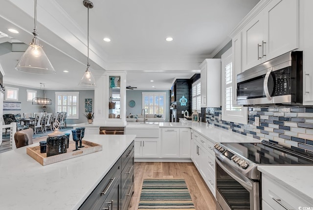 kitchen featuring appliances with stainless steel finishes, light hardwood / wood-style flooring, white cabinets, and crown molding