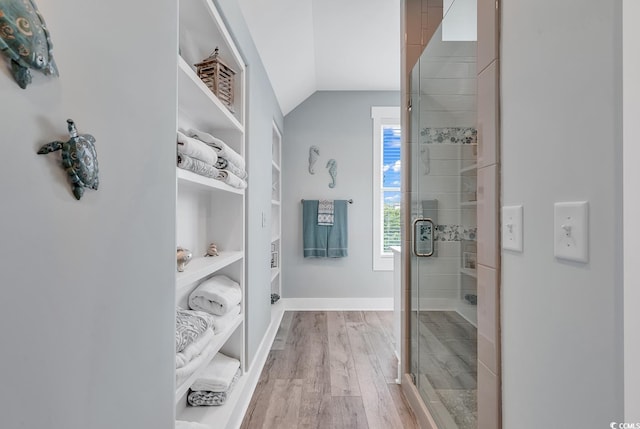 bathroom with walk in shower, wood-type flooring, and vaulted ceiling