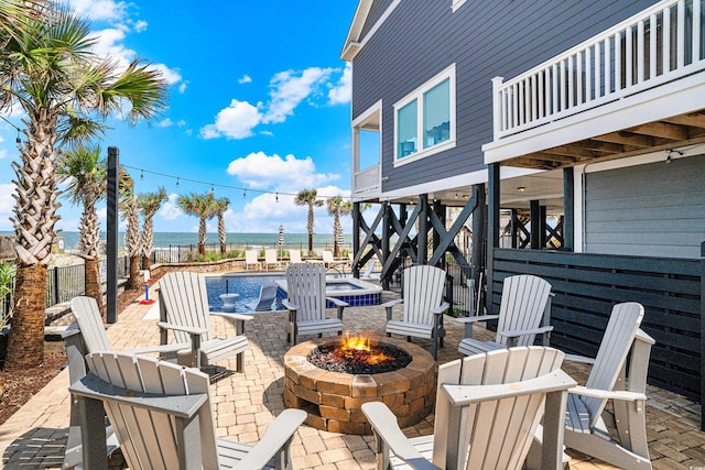 view of patio with a water view, an outdoor fire pit, and a jacuzzi