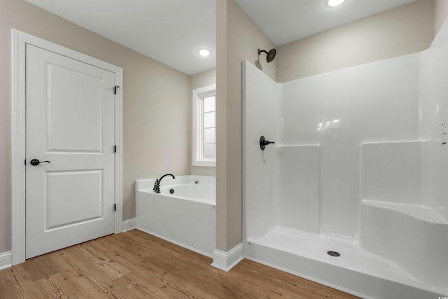 bathroom with baseboards, walk in shower, recessed lighting, wood finished floors, and a bath