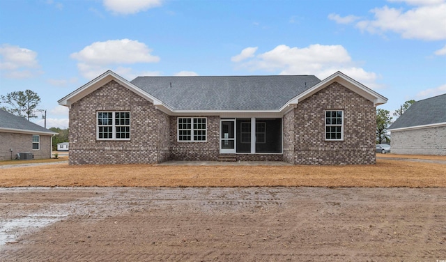 view of front of home featuring brick siding, central AC unit, and roof with shingles