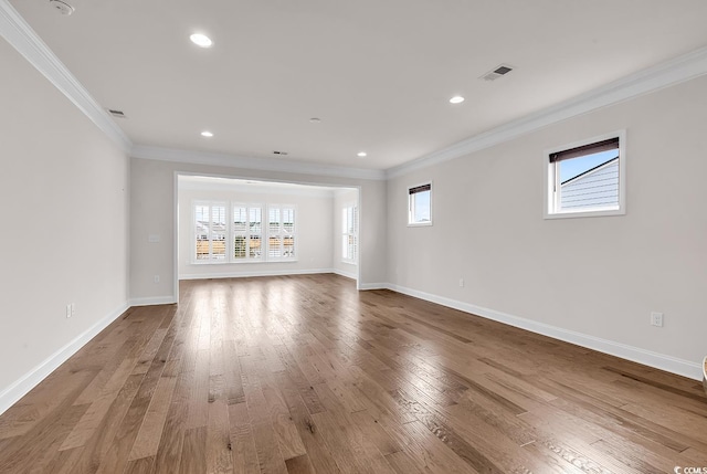 unfurnished living room with hardwood / wood-style flooring, a wealth of natural light, and crown molding