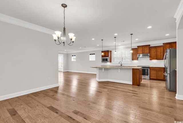 kitchen featuring appliances with stainless steel finishes, light wood-type flooring, a breakfast bar, a kitchen island with sink, and pendant lighting