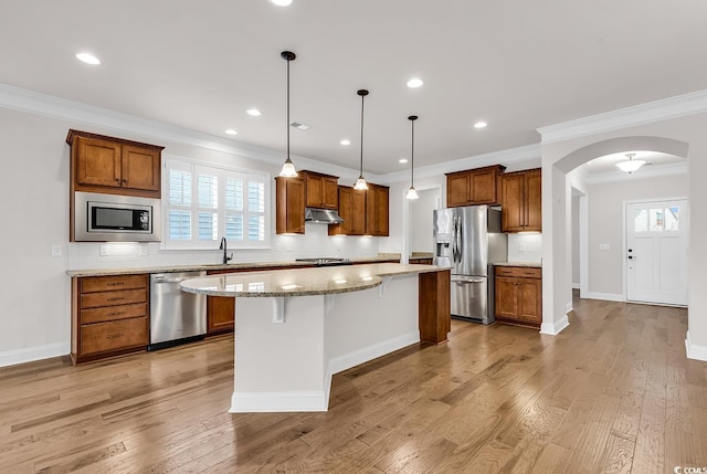 kitchen featuring a kitchen island, crown molding, light wood-type flooring, and stainless steel appliances