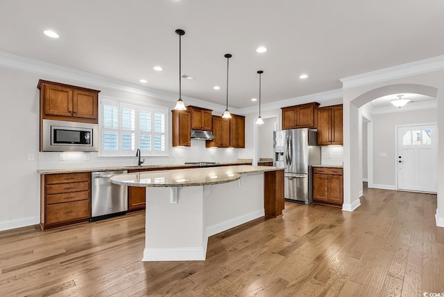 kitchen featuring light hardwood / wood-style flooring, a kitchen island, stainless steel appliances, and ornamental molding