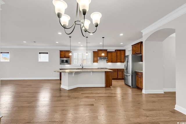 kitchen with appliances with stainless steel finishes, light hardwood / wood-style floors, a kitchen island, hanging light fixtures, and a breakfast bar area