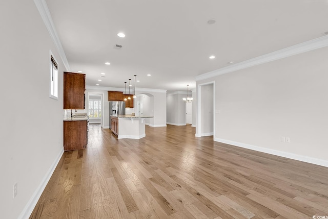 unfurnished living room featuring light wood-type flooring and crown molding