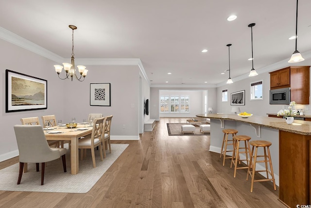 dining area featuring ornamental molding, a notable chandelier, and light wood-type flooring