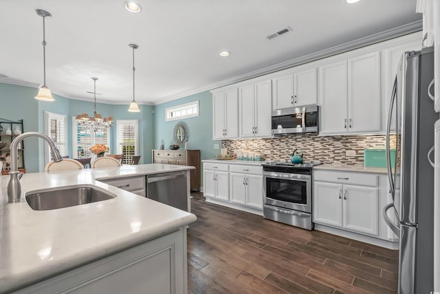 kitchen with appliances with stainless steel finishes, backsplash, decorative light fixtures, crown molding, and dark hardwood / wood-style floors