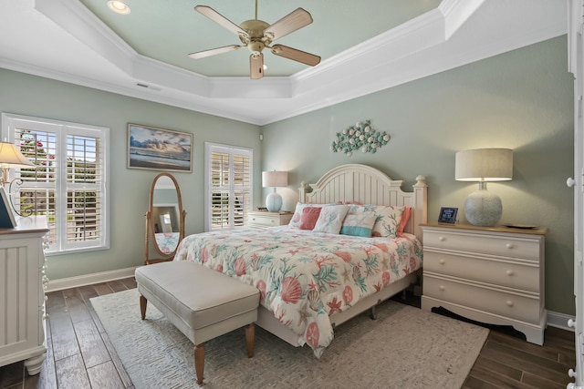 bedroom featuring dark hardwood / wood-style flooring, multiple windows, and a tray ceiling