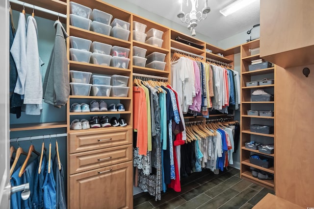 spacious closet featuring dark hardwood / wood-style flooring and a chandelier