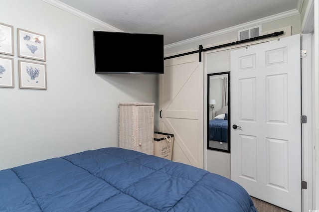 bedroom featuring ornamental molding, a textured ceiling, and a barn door