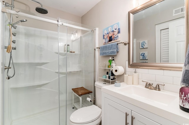 bathroom with vanity, toilet, decorative backsplash, and an enclosed shower