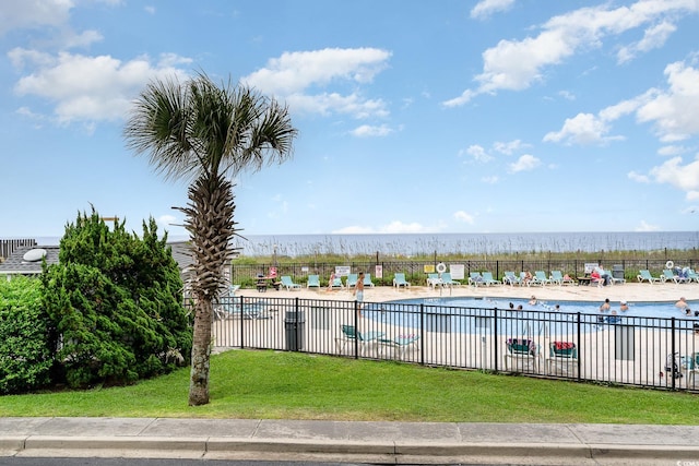 view of pool with a water view and a lawn