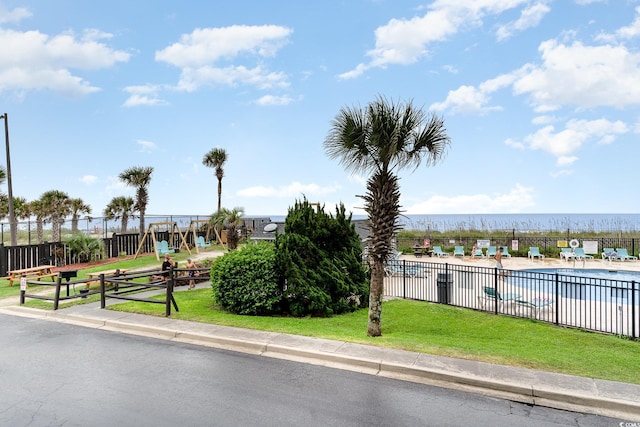 exterior space with a water view, a lawn, and a swimming pool