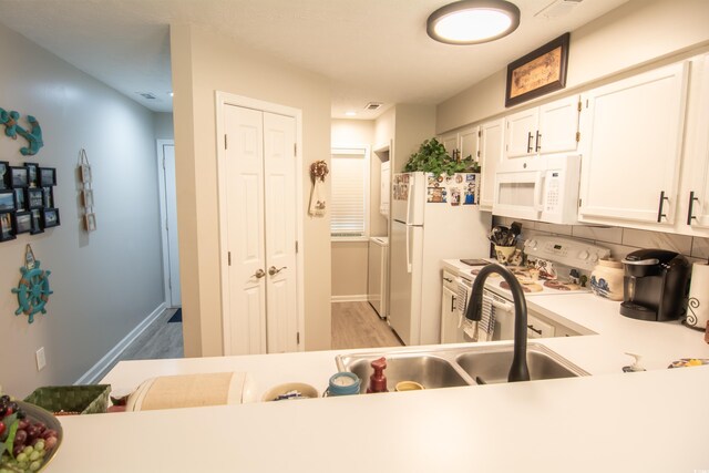 kitchen with light hardwood / wood-style floors, white cabinetry, decorative backsplash, and white appliances