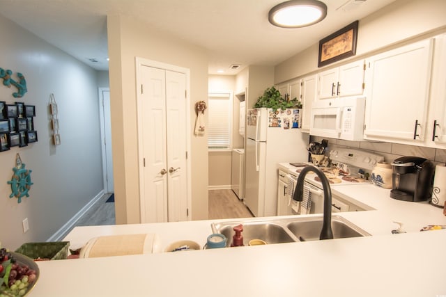 kitchen with white appliances, white cabinets, light countertops, light wood-type flooring, and tasteful backsplash