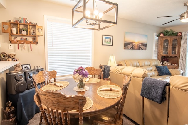 dining space with carpet floors and ceiling fan with notable chandelier