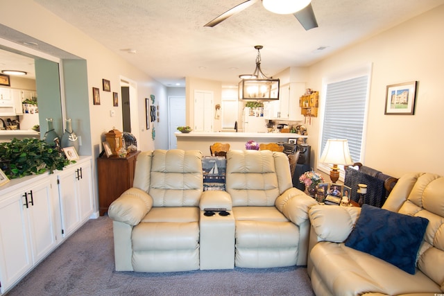 living room with a textured ceiling, ceiling fan with notable chandelier, and carpet flooring