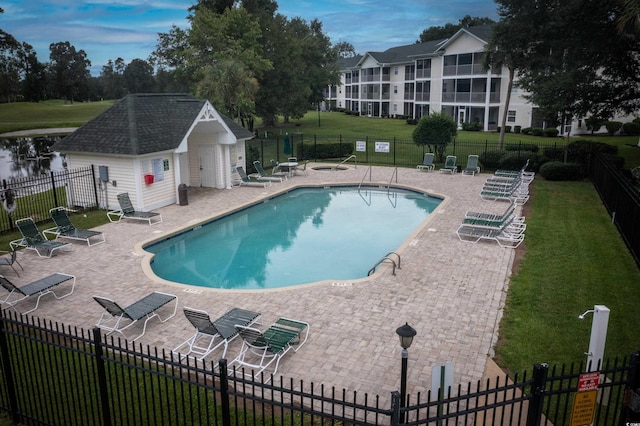 view of pool with a patio, an outdoor structure, and a lawn