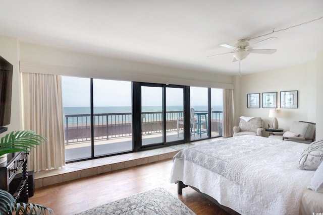 bedroom featuring access to outside, a water view, and wood finished floors