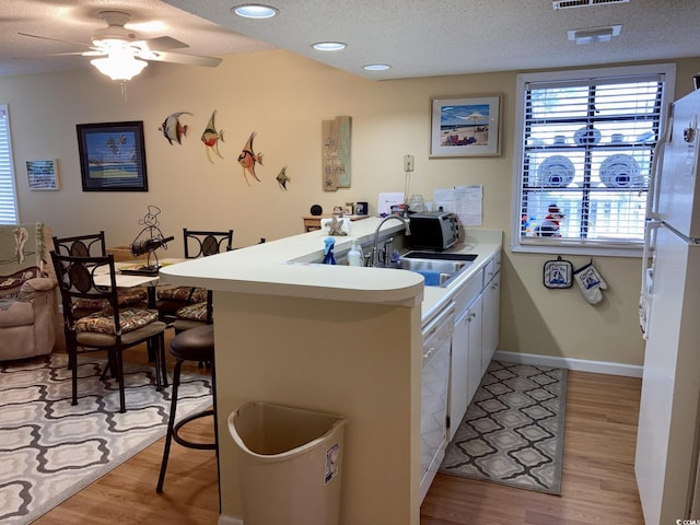 kitchen featuring light hardwood / wood-style flooring, kitchen peninsula, a textured ceiling, ceiling fan, and sink