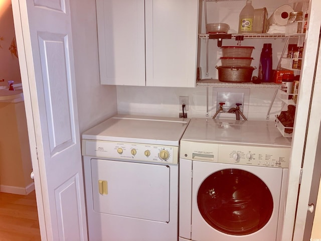 laundry room with separate washer and dryer, light hardwood / wood-style floors, and cabinets