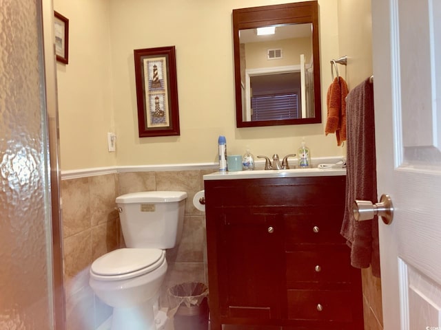 bathroom featuring tile walls, toilet, and vanity