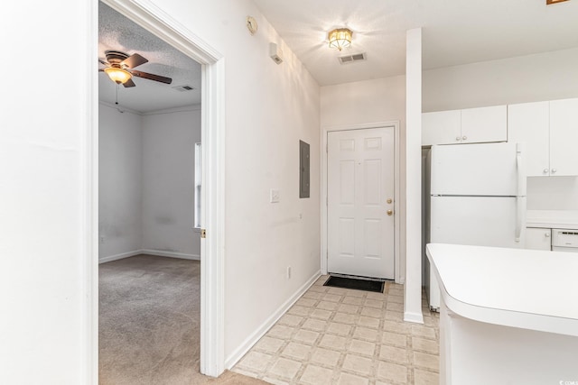 interior space with ceiling fan, white cabinets, a textured ceiling, light carpet, and white fridge