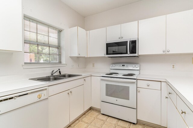 kitchen featuring sink, white appliances, and white cabinetry