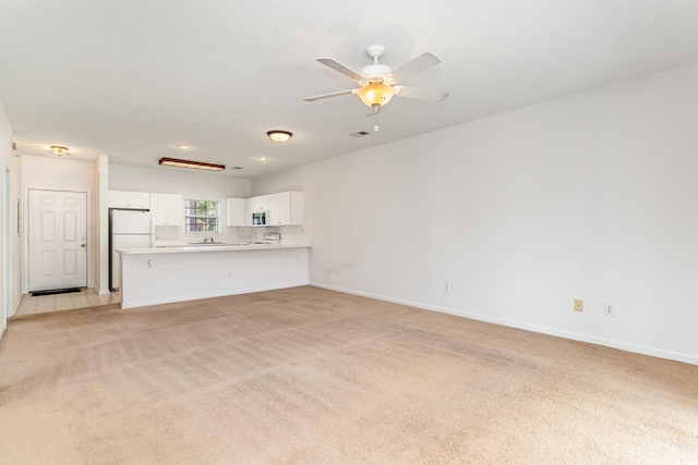 unfurnished living room with ceiling fan, light colored carpet, and sink