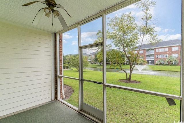 unfurnished sunroom featuring a water view and ceiling fan