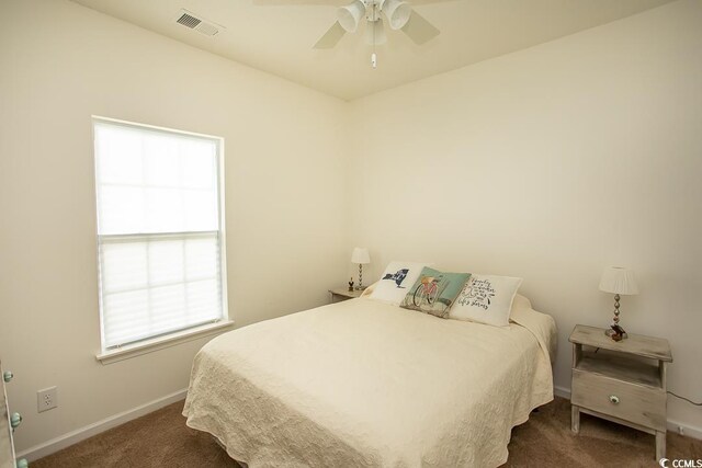 bedroom with ceiling fan, dark carpet, and multiple windows