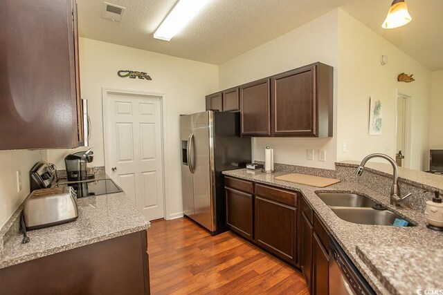 kitchen with dark wood-type flooring, appliances with stainless steel finishes, sink, a textured ceiling, and dark brown cabinets